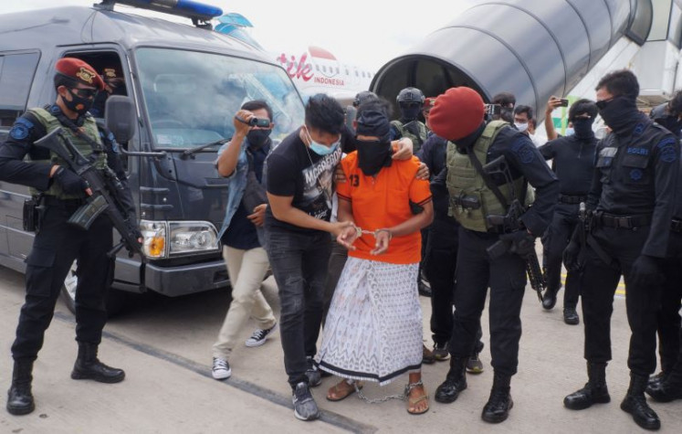 Big catch: Personnel from the National Police’s Densus 88 counterterrorism squad escort Zulkarnaen (center, in orange shirt), 57, a senior leader of the disbanded terror group Jamaah Islamiyah (JI) linked to Al Qaeda, as he arrives on Dec. 16, 2020, at Soekarno-Hatta International Airport in Tangerang, Banten.