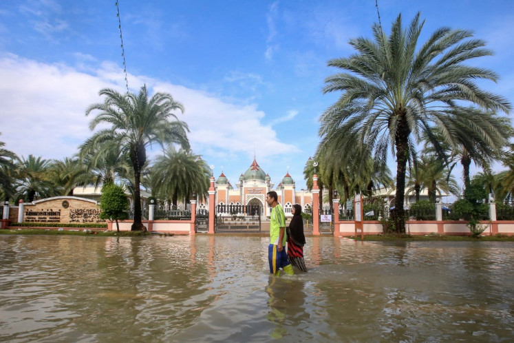 People wade through flood waters outside Pattani Central Mosque following days of heavy rain in Thailand's southern province of Pattani on Dec. 2, 2024. Flooding driven by heavy rains in southern Thailand has killed nine people and displaced more than 13,000, officials said Nov. 30, as rescue teams using boats and jet skis worked to reach stranded residents.