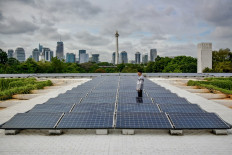 A maintenance officer inspects a rooftop solar power system at Istiqlal Mosque in Central Jakarta on Dec. 5, 2024, the distinctive shape of the National Monument (Monas) visible in the background.