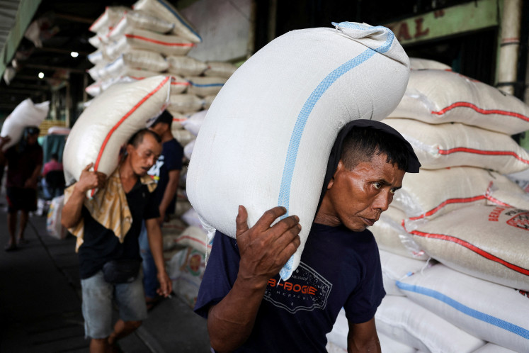 Workers carry sacks of rice at a wholesale market in Jakarta, on Sept. 22, 2025. 