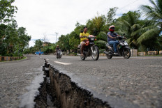 Motorists pass a crack in the road along a major highway in Tabogon town, Cebu province, central Philippines on October 1, 2025, after a 6.9-magnitude quake struck off the coast of the central Philippines. The earthquake jolted the central Philippines, collapsing buildings and killing at least 31 people on the island of Cebu, authorities said on October 1, with fears the toll could rise as rescuers searched for survivors.