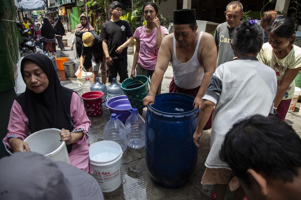 Residents line up with a variety of containers to buy clean water on March 14, 2025, amid a days-long water outage in a Jakarta neighborhood.