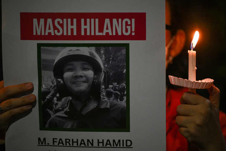 An activist hold a poster showing Muhammad Farhan Hamid, a protester who went missing during the string of antigovernment protests in Jakarta in late August, during a vigil in Bendungan Hilir, Central Jakarta on Sept. 30, 2025 to commemorate the August protest which led to the death of at least 10 people and hundreds of others detained by the police.