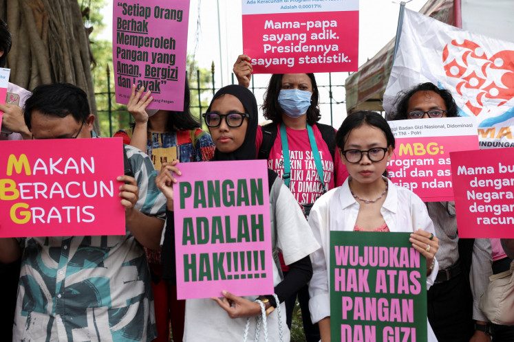 People carry placards on Oct. 2, 2025 during a protest against the government’s free nutritious meal program, in Jakarta. Increasing numbers of people are questioning the program’s efficacy and safety following mounting food-poisoning incidents.