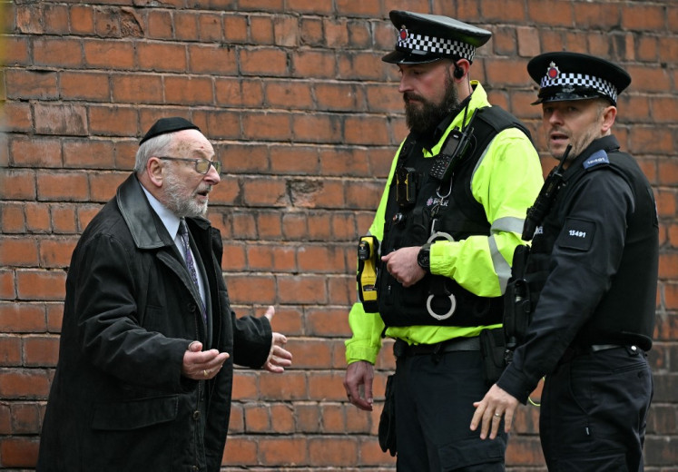 Police officers talk with a member of the local community near Heaton Park Hebrew Congregation synagogue in Crumpsall, north Manchester, on October 2, 2025, following an attack at the synagogue. Two people were killed and three wounded in a car ramming and stabbing incident outside a synagogue in Manchester, northwest England, on Thursday. 