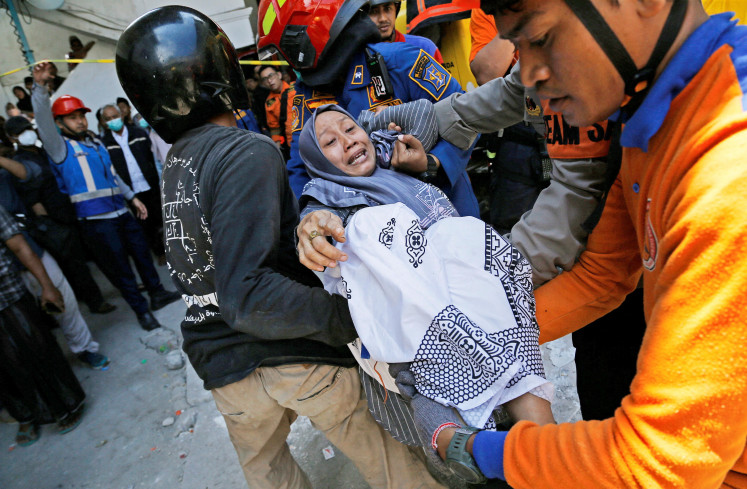 Members of the National Search and Rescue Agency (Basarnas) carry a relative of the victim of a collapsed building, after a hall collapsed while students were praying at the Al-Khoziny Islamic boarding school on Sept. 29, in Sidoarjo, East Java, Oct.1, 2025. 