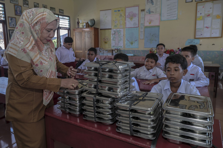 A teacher prepares to distribute lunch boxes from the free nutritious meal program to elementary school pupils in Ternate, North Maluku, on Sept. 30. President Prabowo Subianto has said the program has reached nearly 30 million beneficiaries, delivering more than 1 billion nutritious meals to children across Indonesia, while also significantly boosting the economy by creating an estimated 1.5 million new jobs by January–February 2026.