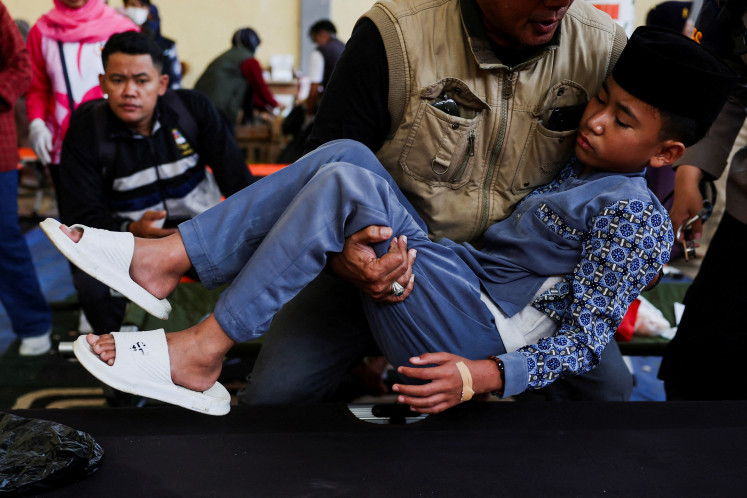 A local official carries Muhammad Nizam, 13, a student diagnosed with food poisoning after eating a meal provided through the government-sponsored free nutritious meal program, at a makeshift clinic set up on Sept. 25, 2025, at a district building in Bandung, West Java.
