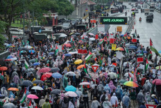 People walk with umbrellas in the rain as they take part in protest near the US embassy against Israel's interception of a Gaza-bound aid flotilla and the detention of at least 12 Malaysian activists, in Kuala Lumpur on October 3, 2025. 