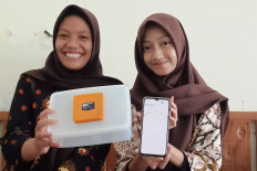 Alya Meisya and Felda Triana of SMA 2 Cilacap state senior high school In Cilacap, Cental Java, showcase their smart lunchbox and app designed to detect spoiled food on Oct. 2, 2025. Their invention aims to prevent food poisoning linked to the government’s free meals program.