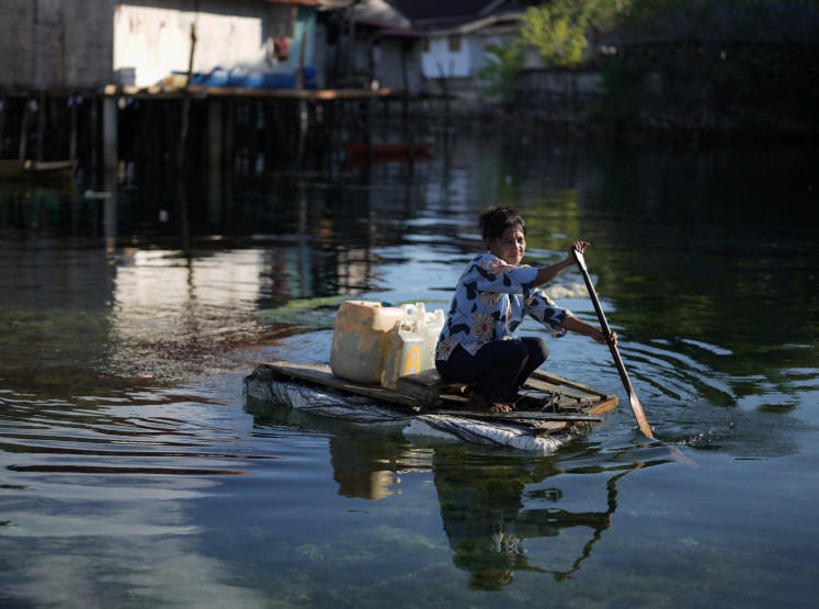 A Bajo woman transports clean water in containers on a small boat on Oct. 3 in Bakti village, Wakatobi, Southeast Sulawesi. 