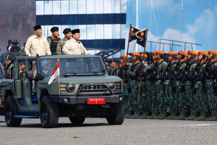 President Prabowo Subianto, accompanied by Defense Minister Sjafrie Sjamsoeddin and Indonesian Military (TNI) commander Gen. Agus Subiyanto, stands on a military vehicle while inspecting the troops during the 80th TNI anniversary celebrations at the National Monument (Monas) complex in Jakarta, Oct.5, 2025. 