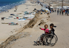 Hope amid despair: Displaced Palestinian children sit in a wheelchair by the side of a road on Saturday, after Hamas agreed to release hostages and accept some other terms in a United States plan to end the war, in the central Gaza Strip.