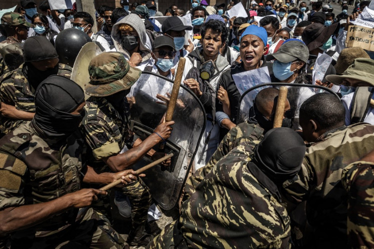 Medical students react as they are pushed with shields and clubs by Malagasy security forces during a demonstration calling for improved healthcare conditions and constitutional reforms in Antananarivo, on October 7, 2025. President Andry Rajoelina's appointment of an army general as new prime minister was met with little enthusiasm in Madagascar Tuesday and dismissed by the youth-led movement behind two weeks of protests as a diversion.