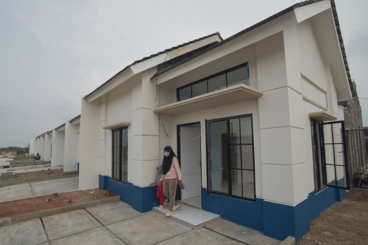 A woman and her child walk out of a subsidized house for media industry workers at the Gran Harmoni Cibitung Residential Complex in Bekasi, West Java, on June 5, 2025.