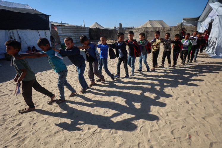 Palestinian pupils walk in a queue out of a tent used as a classroom at a school set up by the Mayasem Association for Culture with UNICEF support, at a displacement camp in the al-Qarara area of Khan Yunis in the southern Gaza Strip on October 7, 2025. 