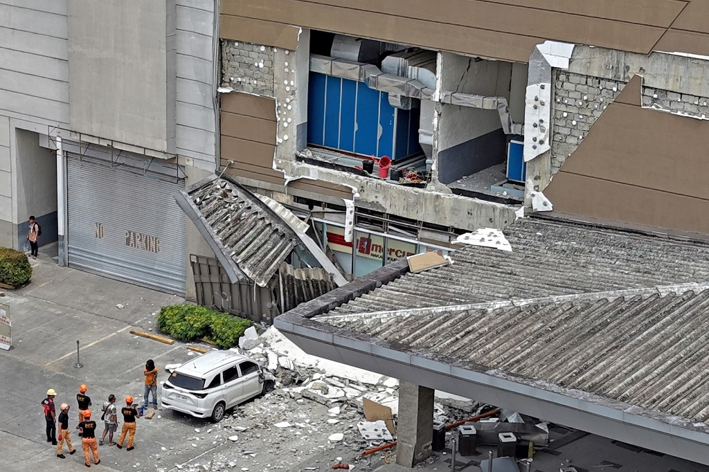Authorities inspect a damaged wall and a car outside a mall in Butuan City, on the southern island of Mindanao on October 10, 2025, after a 7.4-magnitude earthquake struck off the southern Philippines. A powerful magnitude-7.4 earthquake struck off the southern Philippines on October 10, triggering warnings of a “destructive tsunami“ on the country's Pacific coast within hours.