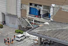 Authorities inspect a damaged wall and a car outside a mall in Butuan City, on the southern island of Mindanao on October 10, 2025, after a 7.4-magnitude earthquake struck off the southern Philippines. A powerful magnitude-7.4 earthquake struck off the southern Philippines on October 10, triggering warnings of a “destructive tsunami“ on the country's Pacific coast within hours.