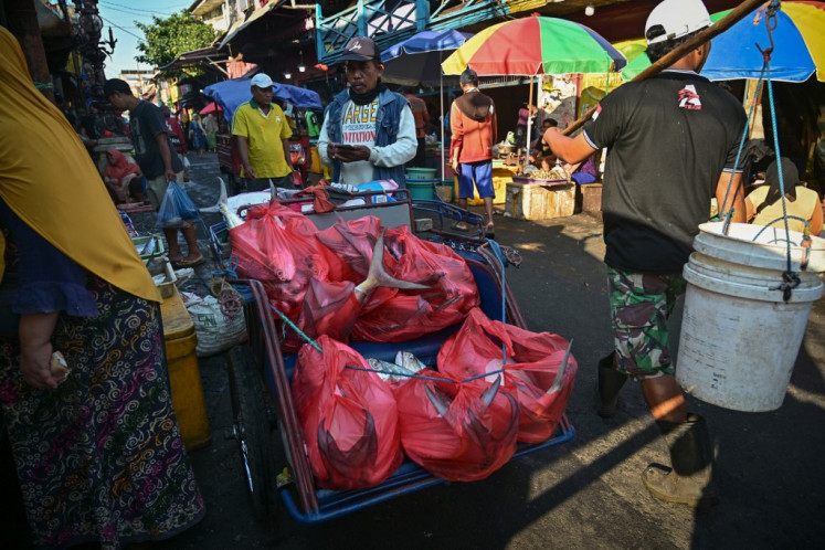 A becak (pedicab) driver delivers fish packed in plastic bags at a traditional fish market on Oct. 9 in Surabaya, East Java.