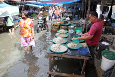 Vendors and visitors at a traditional market in Medan Labuhan District, North Sumatra, carry on with their usual activities amid ankle-deep floodwaters on Oct. 13, 2025. Heavy rainfall on Saturday and early Sunday triggered widespread flooding across the city, that affected more than 10,000 residents.