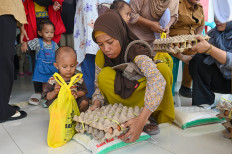 A woman collects a tray of eggs on Oct. 15, 2025, during an anti-stunting food distribution event organized by the municipal administration of Palu, Central Sulawesi.