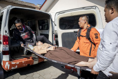 Health workers evacuate students suspected of food poisoning on Oct. 14, 2025, after eating free nutritious meals at SMP 1 Cisarua state junior high school in West Bandung regency, West Java. According to school officials, 54 students reportedly fell ill after consuming the meals served that morning.