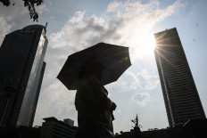 A Jakarta resident uses an umbrella during scorching weather on Oct. 15 at the Hotel Indonesia traffic circle. 