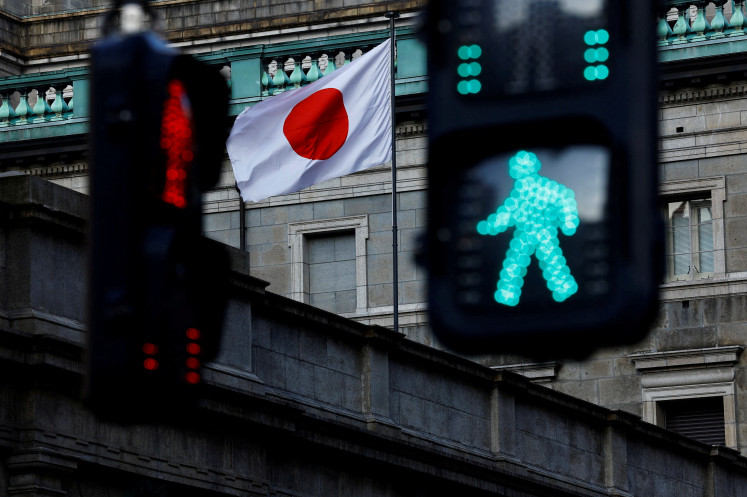 The Japanese national flag hoisted atop of the Bank of Japan headquarters is seen between traffic signals in Tokyo  on Jan. 23, 2025.