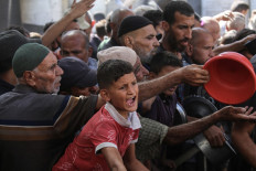 A boy reacts as Palestinians gather to receive food portions from a charity kitchen in the Nuseirat refugee camp, located in the central Gaza Strip, on October 15, 2025, two days after a ceasefire came into effect. Israel was expected to allow Gaza's sole border crossing to the outside world to reopen on October 15 to allow aid into the devastated territory as part of a US-backed ceasefire deal. 