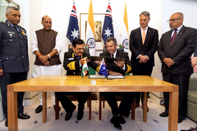Indian Defense Minister Rajnath Singh (second left) and his Australian counterpart Richard Marles (second right) watch Australian Rear Admiral Matt Buckley (third right) and Indian Vice Chief of Naval Staff Vice Admiral Sanjay Vatsayan (third left) sign a defense agreement on Oct. 9 at Parliament House in Canberra.