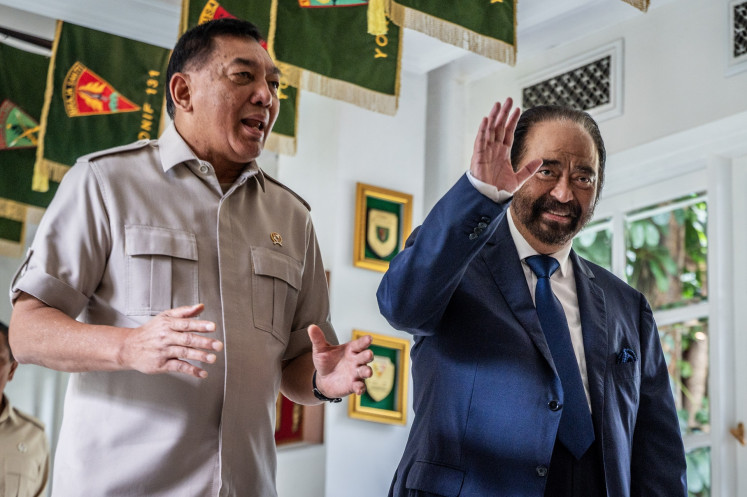 Defense Minister Sjafrie Sjamsoeddin (left) and NasDem Party chair Surya Paloh (right) greet journalists upon walking to a meeting room at the Defense Ministry's office in Jakarta on Oct. 15, 2025. The minister hosted the politician-cum-businessman to talk about matters pertaining to the nation's stability and sovereignty, he said after the meeting.