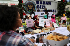 Protesters hold placards on Oct. 15 outside the National Nutrition Agency (BGN) building in Jakarta during a rally demanding an end to President Prabowo Subianto's flagship free nutritious meal program following cases of food poisoning in schools.