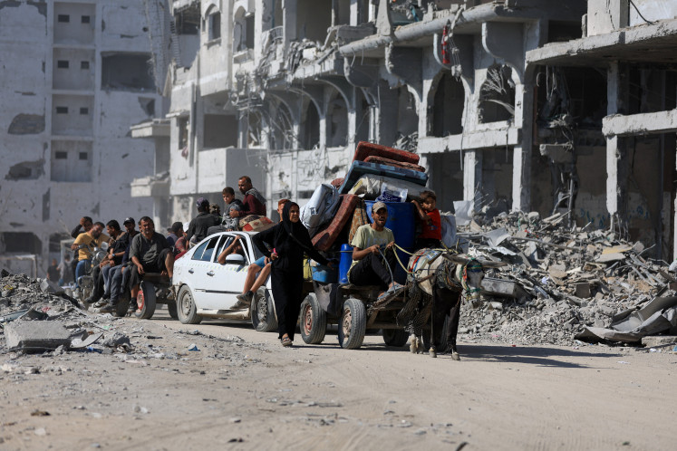 Palestinians ride on an animal-drawn cart on Oct. 16 past the rubble of destroyed buildings, amid a ceasefire between Israel and Hamas, in Gaza City, Palestine.