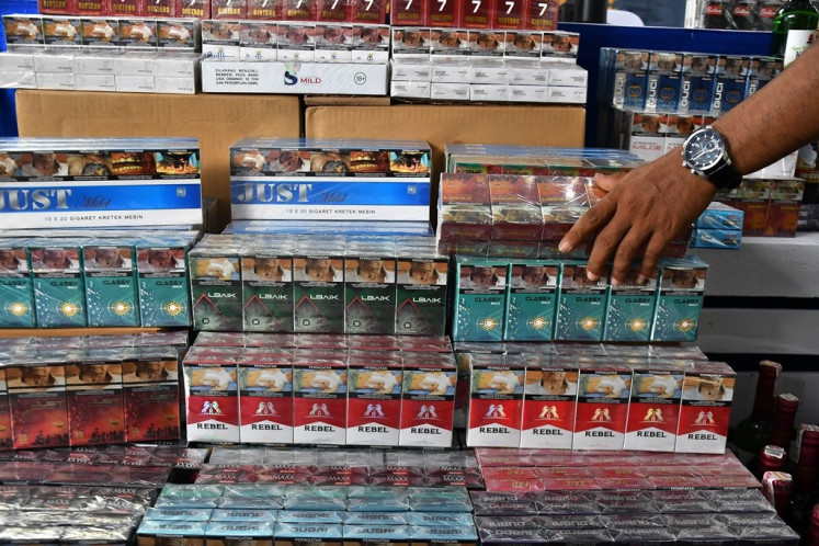 A Bekasi customs and excise official displays confiscated illegal cigarette packages set to be destroyed in Bekasi Regency, West Java on Dec. 6, 2023.  
