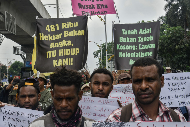 Protesters hold posters and banners that read '481,000 hectares is not just number, but our lives!' (left) and 'Customary land is not empty land' (right) during a rally in front of the Agrarian and Spatial Planning Ministry in Jakarta on Oct. 7, 2025, to protest deforestation that threatens indigenous land in South Papua.