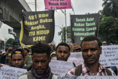 Protesters hold posters and banners that read '481,000 hectares is not just number, but our lives!' (left) and 'Customary land is not empty land' (right) during a rally in front of the Agrarian and Spatial Planning Ministry in Jakarta on Oct. 7, 2025, to protest deforestation that threatens indigenous land in South Papua.
