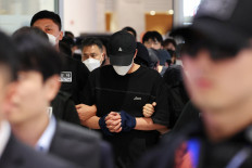Police officers escort South Korean deportees suspected of being involved in online scam operations in Cambodia upon their arrival at the Incheon International Airport in Incheon, South Korea, on Oct. 18, 2025.