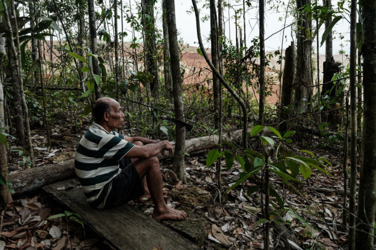 Ngigoro, 62, an elder of the Hongana Manyawa indigenous tribe who left the forest and now lives in a village with his mother, watches a nickel mining site from the edge of the forest on April 16 in East Halmahera, North Maluku.