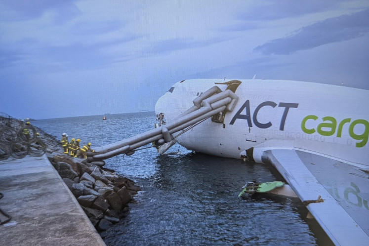 This handout photo taken and released on October 20, 2025 by Airport Authority Hong Kong shows a Boeing 747-400 cargo aircraft after it hit a ground vehicle during landing on the north runway of Hong Kong's international airport and skidded into the sea, killing two. 