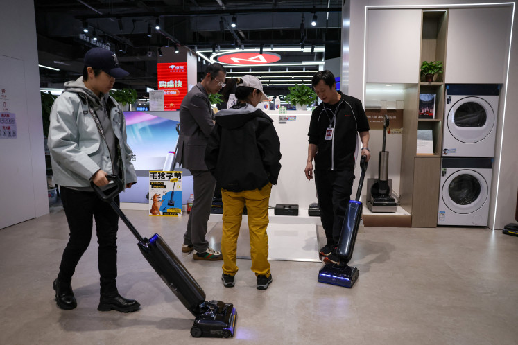 A staff member promotes a vacuum cleaner to customers at a home appliance mall in Beijing on Oct. 19, 2025.