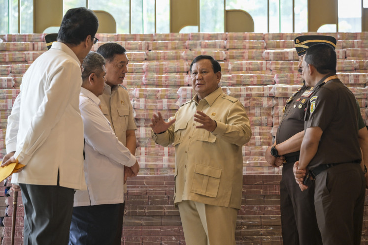 President Prabowo Subianto (‘center') speaks to his cabinet members, including Attorney General Sanitiar Burhanuddin ('second right'), Defense Minister Sjafrie Sjamsoeddin ('third left') and Finance Minister Purbaya Yudhi Sadewa (‘left'), at the Attorney General’s Office in Jakarta on Monday, October 20, in front of stacks of rupiah banknotes worth US$780 million. The pile of cash was shown to journalists during the handover of assets recovered from a corruption case involving the provision of crude palm oil export facilities.