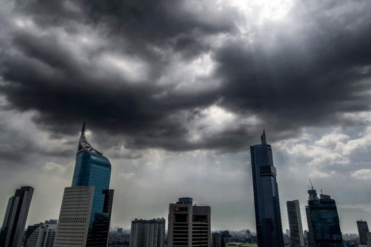 Thick, dark clouds fill the sky above high-rises in Central Jakarta on July 8, 2024, after several days of heavy rain.