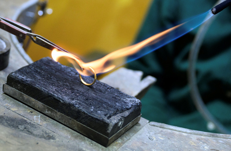 Goldsmith Axel Harbaum-Neuhaus heats up a golden ring for a photo in his local shop in Bonn, Germany, on Oct. 21, 2025, as gold prices rise and many trade in their golden possessions.