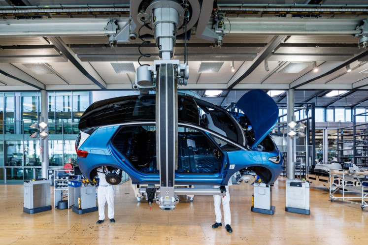 Employees work on the assembly line for the Volkswagen (VW) ID.3 electric car of German carmaker Volkswagen, at the production site of German carmaker Volkswagen in Dresden, eastern Germany, on May 14, 2025.