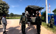 This screengrab from Thai PBS video footage taken on October 22, 2025 and received by AFPTV on October 23, 2025 shows Thai soldiers keeping watch as people, believed to have crossed over to Thailand from Myanmar after escaping from scam centers, board a vehicle in Mae Sot. More than 600 people fled one of Myanmar's most notorious scam centers and crossed into Thailand, after a military raid on the compound. 