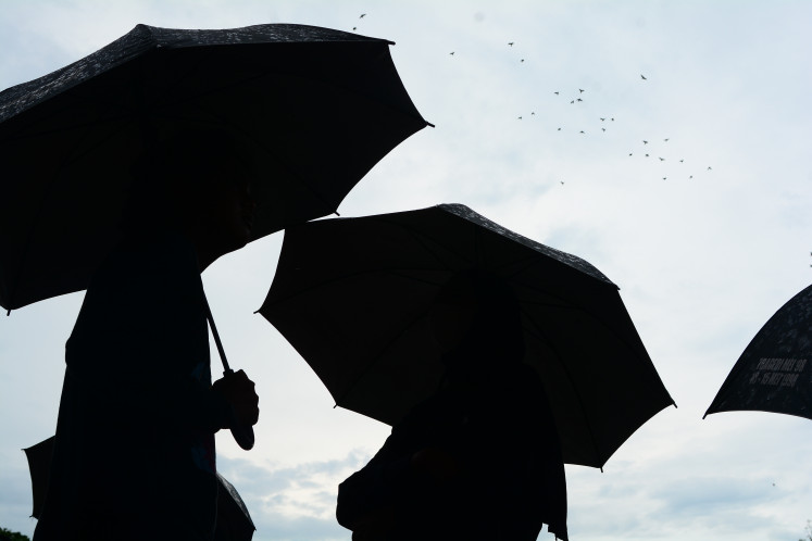 Activists carry umbrellas on Oct. 23, 2025, during the weekly Kamisan (Thursdays) peaceful demonstration in front of the State Palace in Central Jakarta.