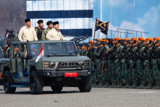 President Prabowo Subianto, accompanied by Defense Minister Sjafrie Sjamsoeddin and Indonesian Military (TNI) commander Gen. Agus Subiyanto, stands on a military vehicle on Sunday while inspecting the troops during the 80th TNI anniversary celebration at the National Monument (Monas) complex in Jakarta.  