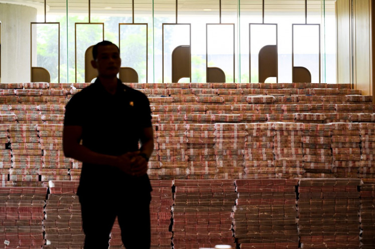 All about money: A member of the Presidential Security Detail guards a large stack of rupiah banknote bundles on Oct. 20, 2025 at the Attorney General’s Office in Kebayoran Baru, South Jakarta, prior to the handover to the state of around Rp 13.2 trillion (US$825 million) seized from companies involved in a corruption case pertaining to illegal crude palm oil (CPO) export permits.