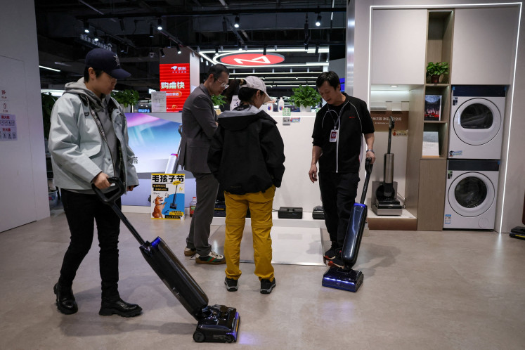 A staff member promotes a vacuum cleaner to customers at a home appliance mall in Beijing, China, on Oct. 19, 2025.