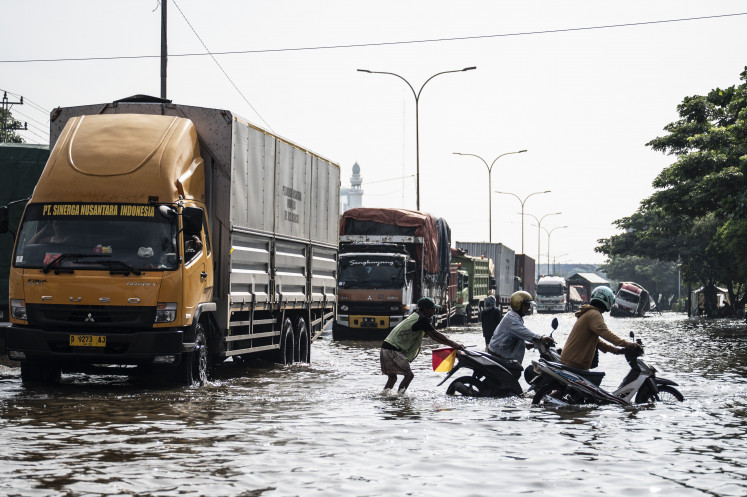 Unstoppable tide: Residents push their motorbikes on Friday through floodwaters that inundated Jl. Kaligawe Raya in Semarang, Central Java, a section of the Java Northern Coast (Pantura) Highway, located between Semarang and Surabaya, East Java.